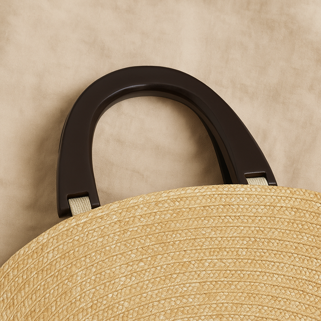 “Close-up of smooth black wooden handles attached to the woven straw clutch, showing fine craftsmanship, by Solmerea.”