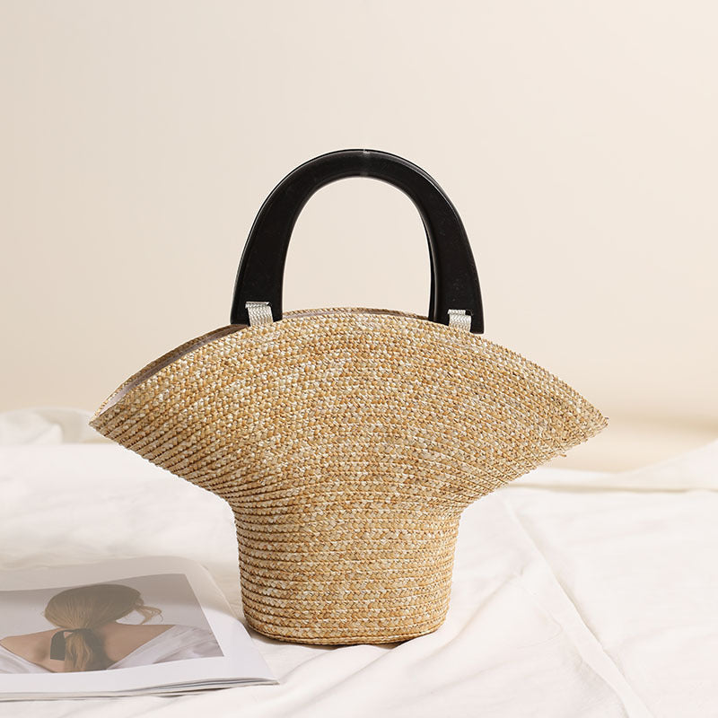 “Natural light studio shot of straw clutch with black wooden handles placed on soft fabric surface, by Solmerea.”