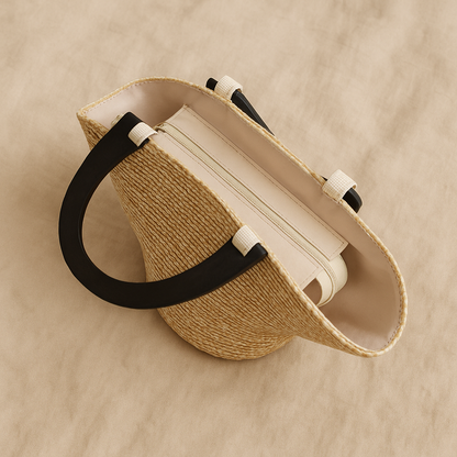“Top view of straw clutch showing cream interior lining and zip closure with black wooden handles, by Solmerea.”