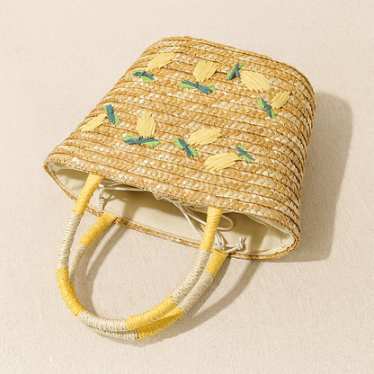 “Handwoven straw tote laid flat showing lemon embroidery pattern and interior lining, by Solmerea.”