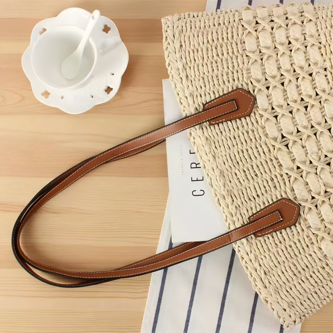 Beige straw shoulder tote on tabletop with leather straps, light summer flatlay, by Solmerea.