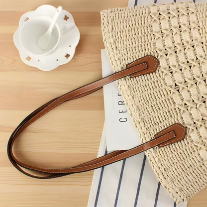 Beige straw shoulder tote on tabletop with leather straps, light summer flatlay, by Solmerea.