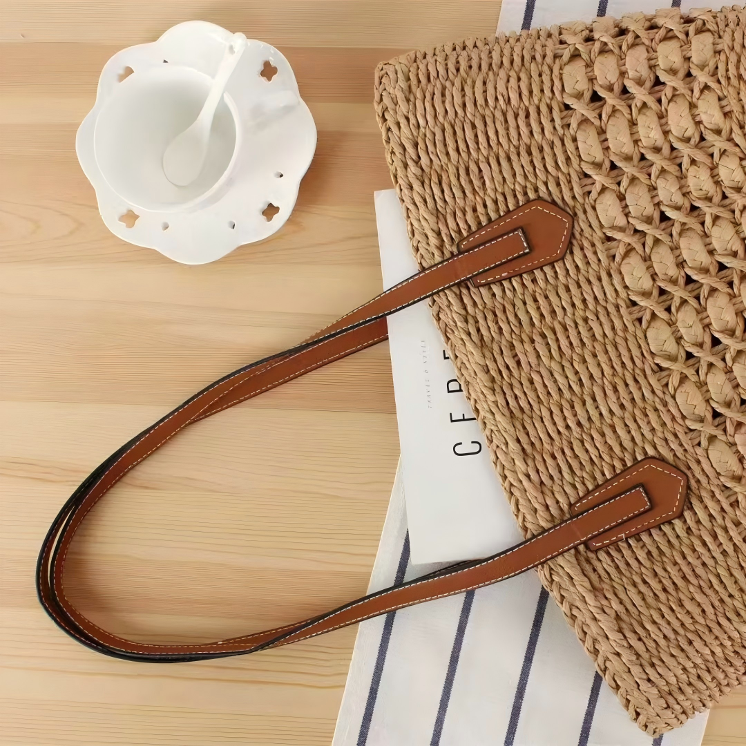 Brown straw shoulder tote on tabletop with leather straps, casual summer flatlay, by Solmerea.