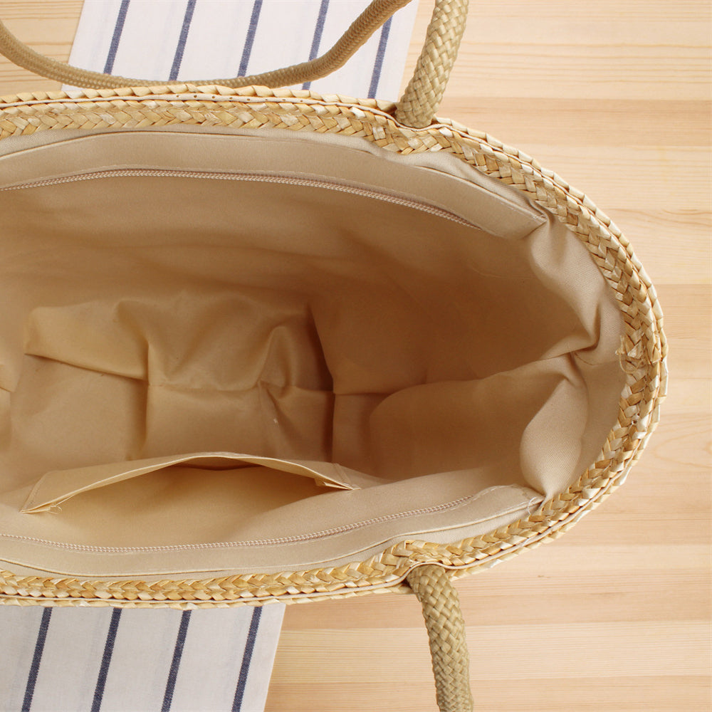 Interior view of straw beach tote bag with spacious beige fabric lining and small inner pocket.