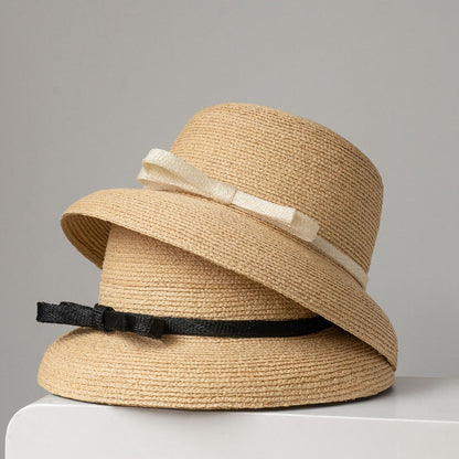 Two straw hats stacked together, featuring white and black ribbon bows, highlighting color variations.