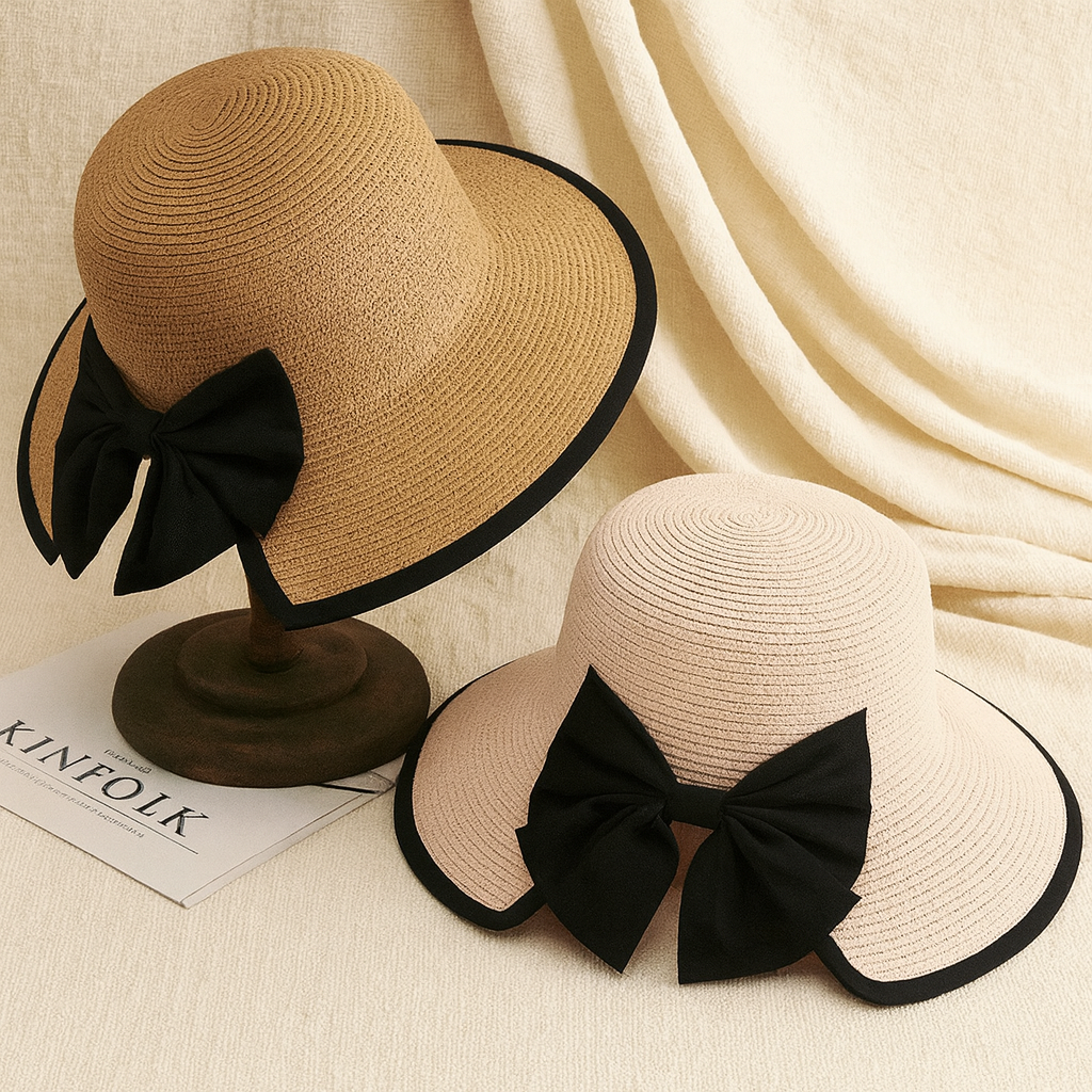 Two straw hats in light and dark beige tones, each featuring a large black bow, displayed on fabric background.