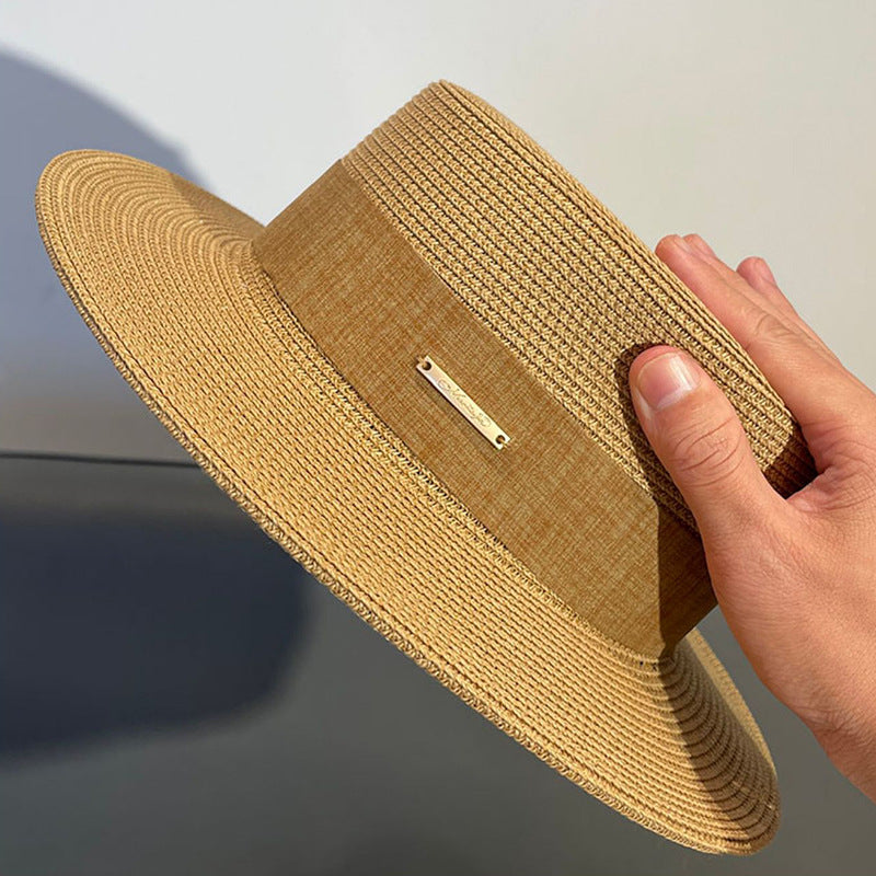Close-up of lightweight straw hat held by hand under sunlight, showcasing woven detail and texture.