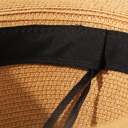 Interior detail of brown straw hat showing black adjustable sweatband with inner tie string.