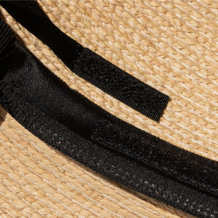 Inside detail of straw hat showing adjustable black band and inner stitching craftsmanship.