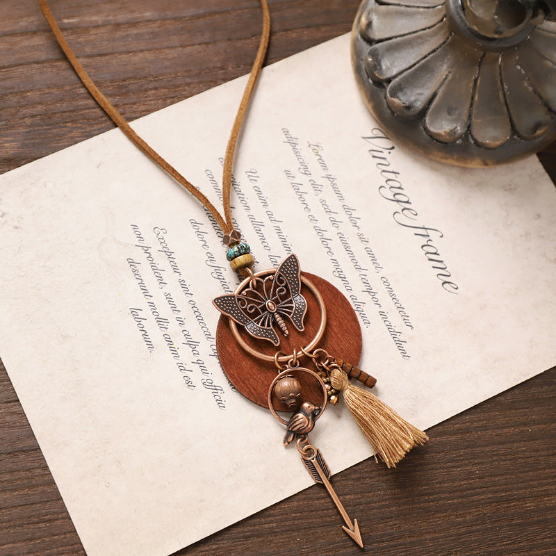 Butterfly pendant wooden necklace with arrow and tassel charms in rustic bohemian style.