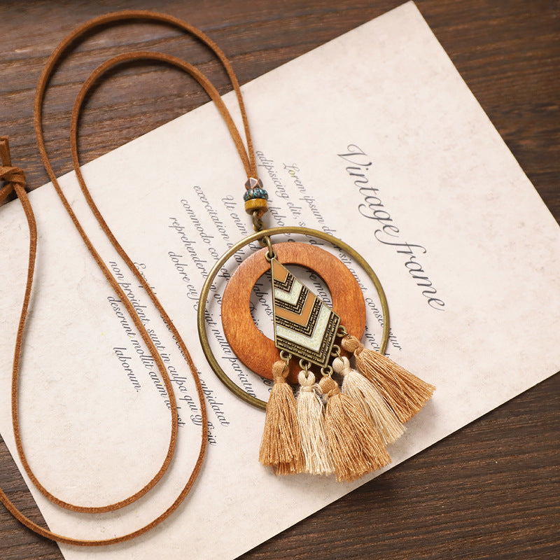 Chevron pendant tassel wooden necklace with layered circles and beige fringe on paper background.