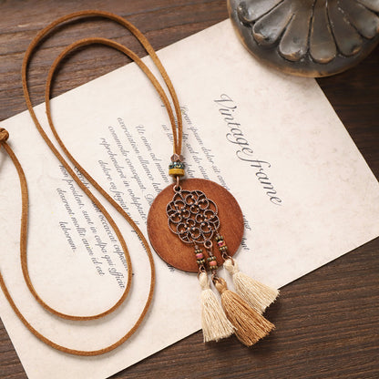 Boho round wooden necklace with filigree floral metal pendant and beige tassels.