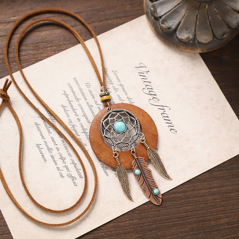 Turquoise feather wooden necklace with dreamcatcher metal design and brown suede cord.