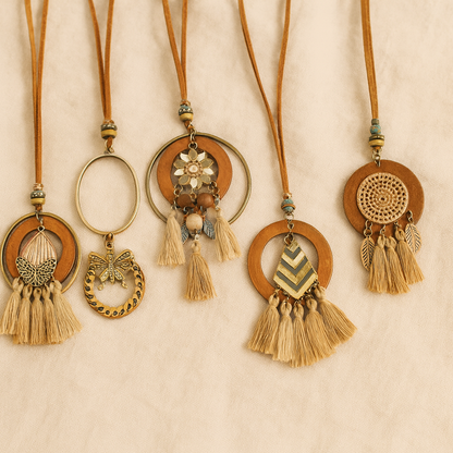 Collection of five tassel wooden necklaces with bohemian designs laid out on beige fabric background.