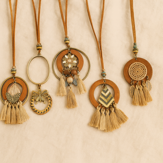 Collection of five tassel wooden necklaces with bohemian designs laid out on beige fabric background.