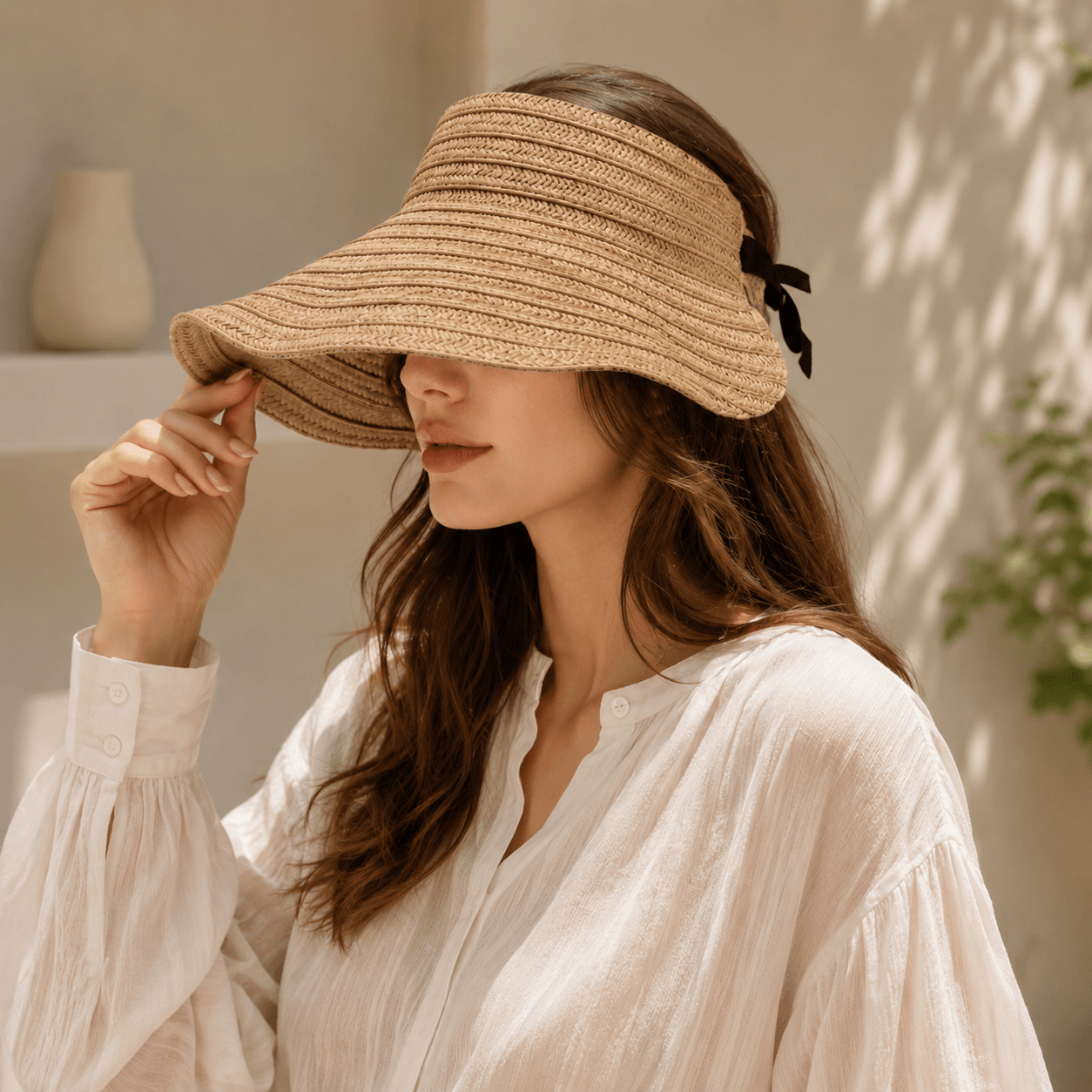 Side view of woman wearing a wide brim woven straw visor hat in natural khaki tone