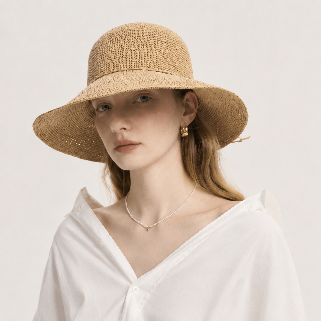 Side profile of woman wearing a natural beige wide brim straw sun hat
