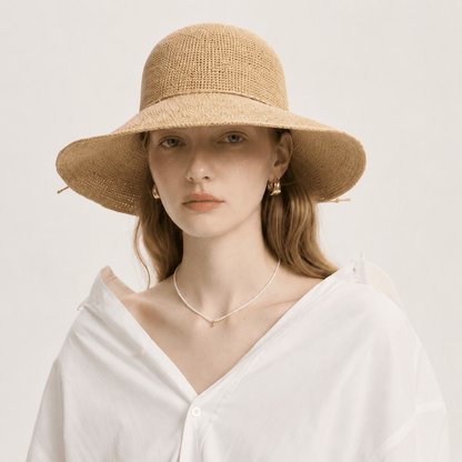 Woman styled in a white blouse wearing a woven wide brim straw hat for summer