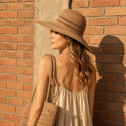 Back view of a woman wearing an openwork wide brim straw sun hat with a woven bag and summer dress