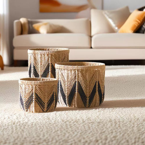 Set of three woven paper rope storage baskets in natural and black zigzag design, displayed in a modern living room.