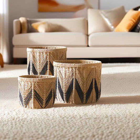 Set of three woven paper rope storage baskets in natural and black zigzag design, displayed in a modern living room.