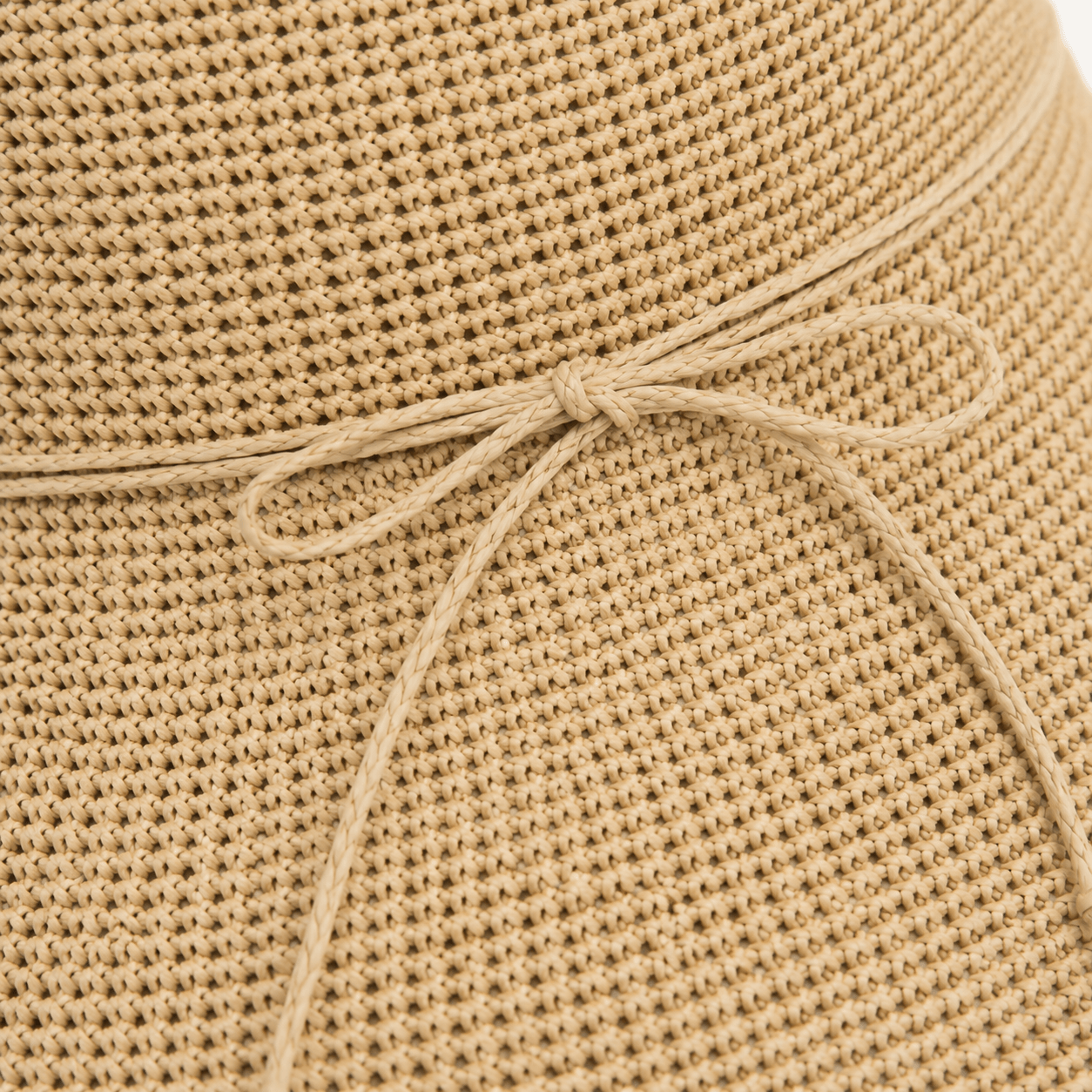 Close-up of woven straw texture and slim bow tie detail on a beige sun hat