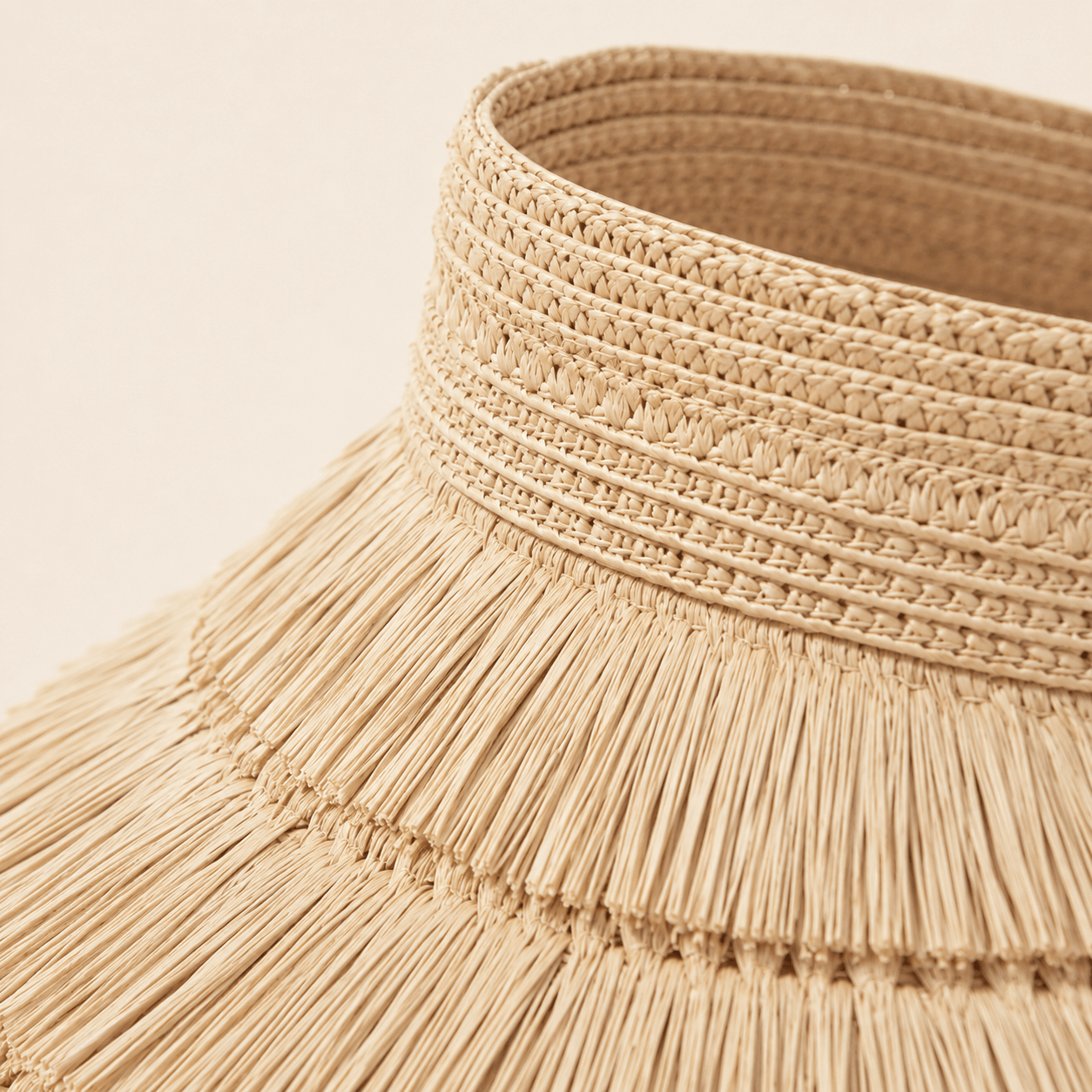 Detailed view of the woven straw texture and layered fringe construction on a sun visor